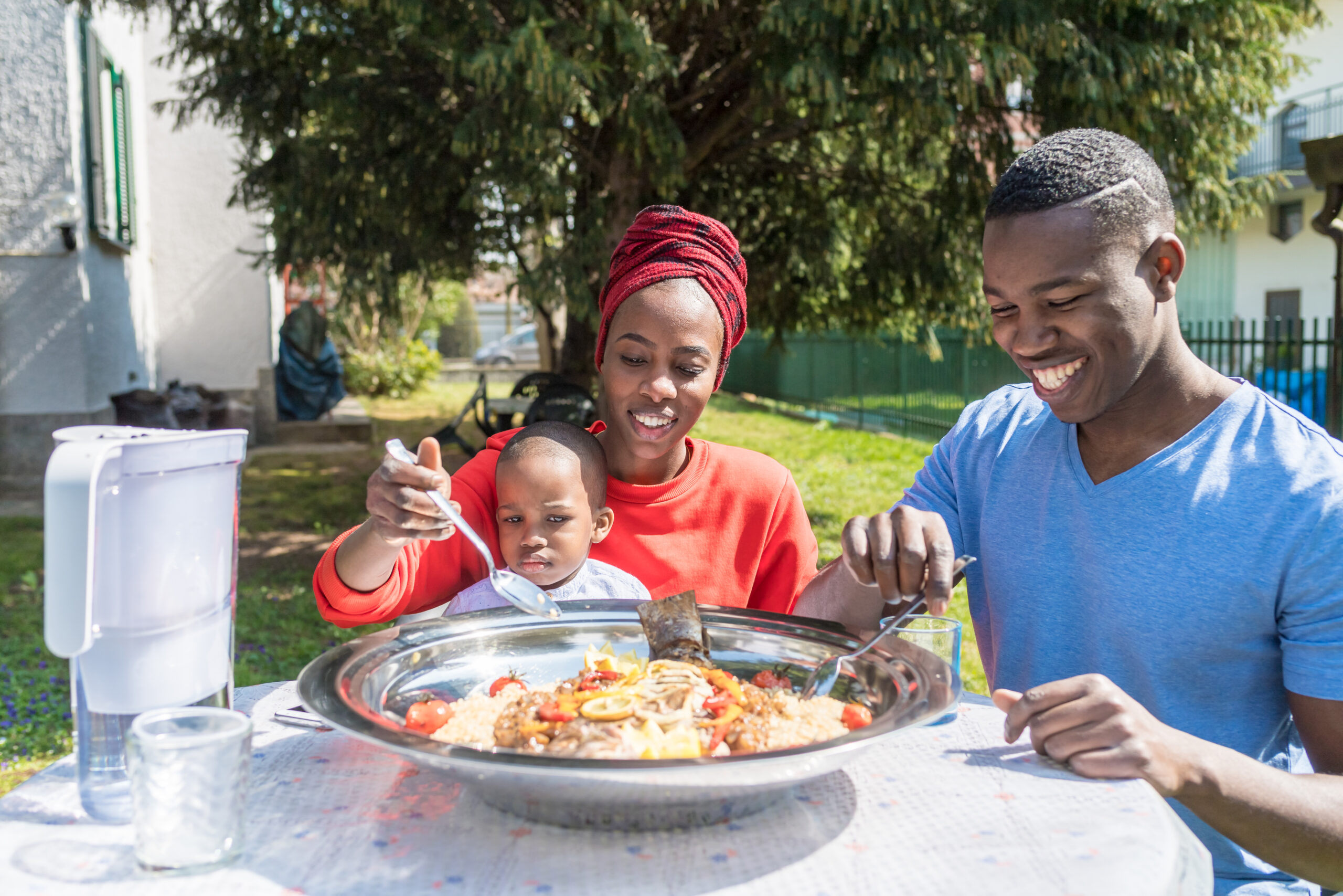 happy family outdoor sitting table having lunch smiling - happiness, conviviality, food concept